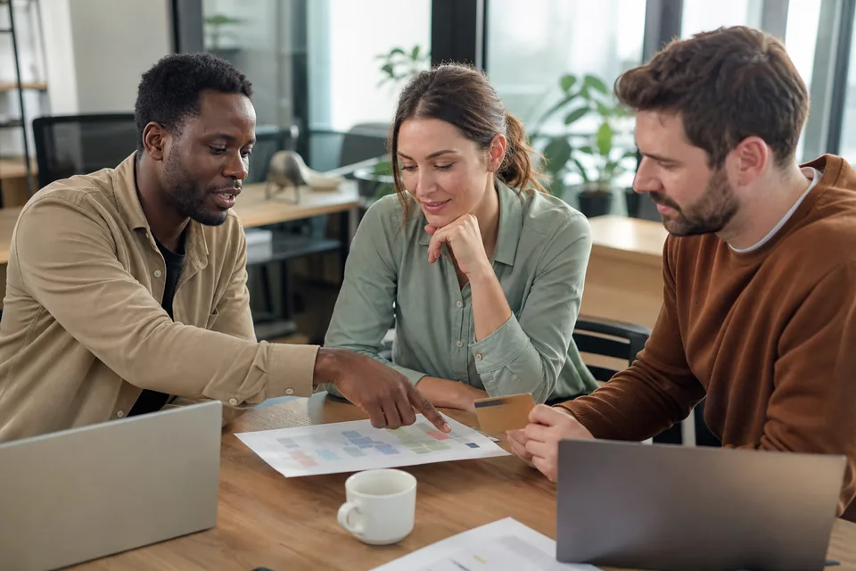 Three sales reps around a table with laptops deciding how many software seats their team needs
